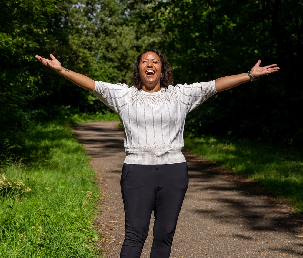 Jessica Meijers geniet veerkrachtig van van het leven na borstkanker te hebben gehad in het bos in de zon met een lach op haar gezicht
